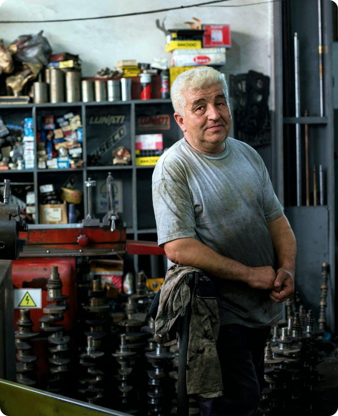 A workshop owner standing among reconditioned engine parts